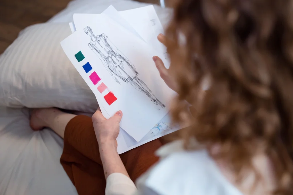 Fashion designer reviewing fabric samples and a sketch before garment production