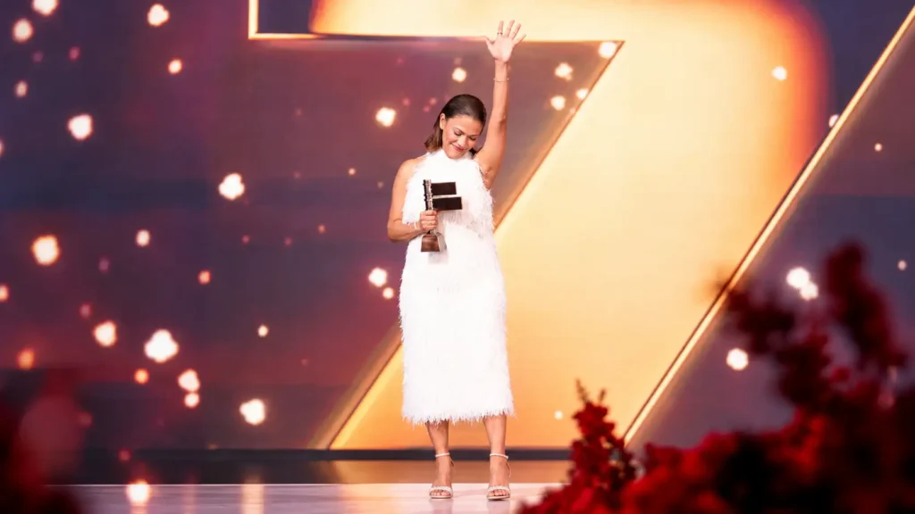Mujer triunfal con trofeo ante el número 7